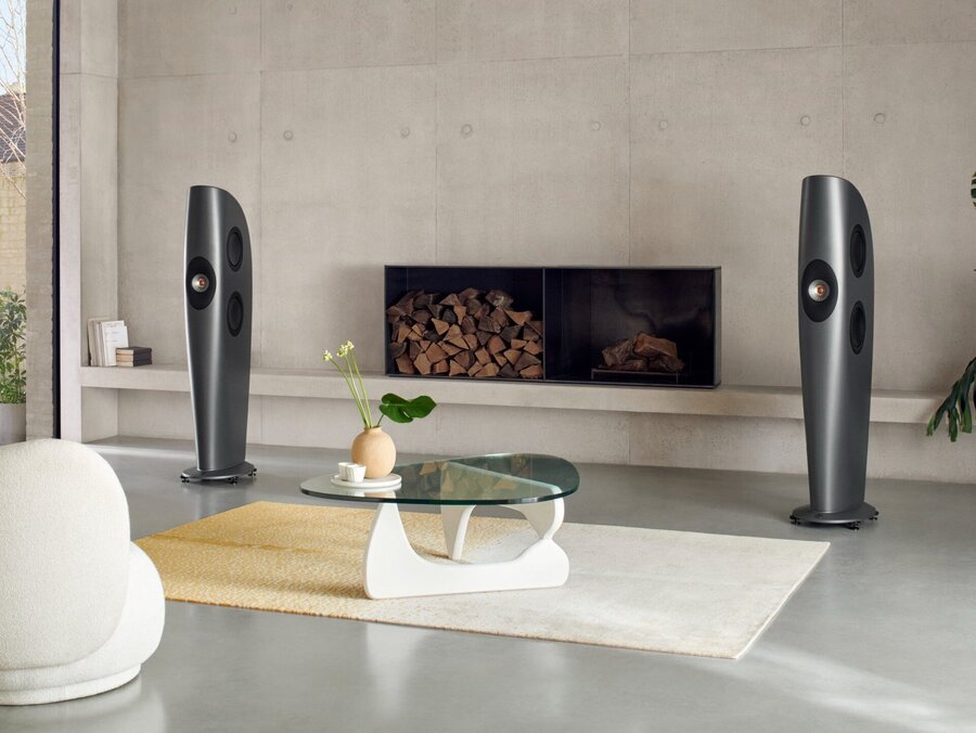 A pair of KEF Blade speakers stand at the sides of an elegant fireplace in a luxury living room.